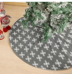 Gray Christmas tree skirt with white snowflakes on wood floor with festive ornaments