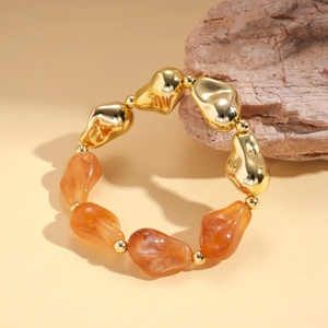 Detail view of retro acrylic beaded bracelet with gold metal and orange resin geometric beads