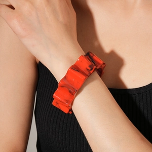 Detail of red marble texture resin bangle with wavy pattern on female model's wrist