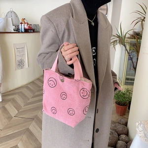 Detailed view of pink corduroy handbag with black smiley print and magnetic closure