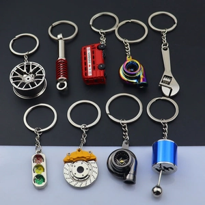 Detail view of various car-themed metal keychains including turbocharger and traffic lights
