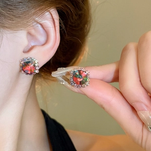 Detailed view of colorful crystal stud earrings with rose gold setting on a model
