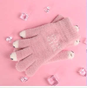 Detail of pink knitted gloves featuring white animal claw tips and Cute Girl text prints