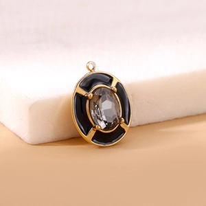 Macro shot of oval gold pendant with clear faceted gemstone and black enamel edge