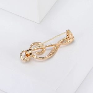 Detail shot of a golden music note brooch featuring a minimalist alloy metal design