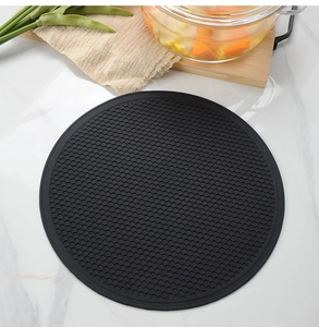Close-up of black round silicone trivet with honeycomb texture on marble countertop