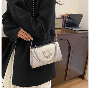 Detail of silver crossbody bag with rhinestone sun clasp and elegant chain shoulder strap