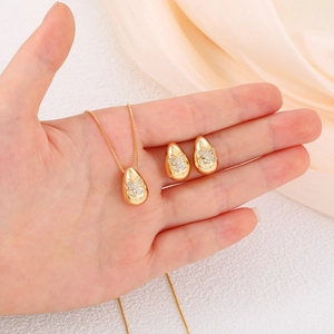 Close-up of gold water drop jewelry set with butterfly zircon inlay on a soft silk background