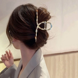 Detailed view of a gold-plated rhinestone hair claw clip worn by a model