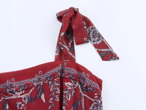 Détail d'une robe en mousseline rouge à fleurs avec bretelle réglable et nœud papillon