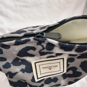 Dettaglio trousse trucco leopardata con zip in metallo nero ed etichetta in tessuto