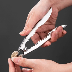 Close-up of a heavy duty stainless steel nutcracker cracking a walnut with hand