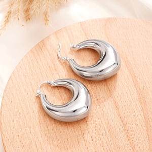 Polished silver teardrop earrings on a wooden display tray with a minimalist aesthetic