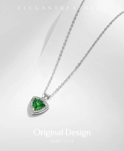 Detail of s925 silver triangle pendant with emerald green gem and sparkling accents