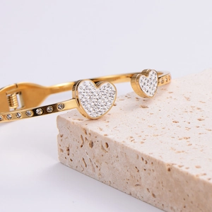 Gold open double heart cuff bracelet featuring sparkling rhinestones on textured stone base