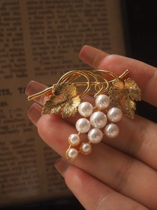 Detailed close-up of a vintage golden grape brooch with elegant white pearl accents