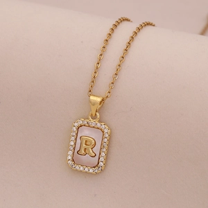 Vue macro du collier en or 18 carats avec pendentif rectangulaire en nacre et lettre R