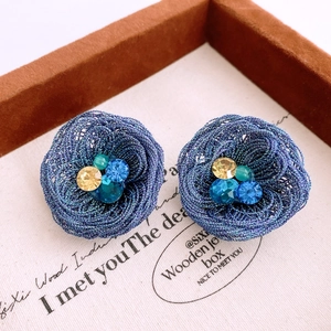 Macro shot of blue woven flower earrings featuring sparkling rhinestone centers