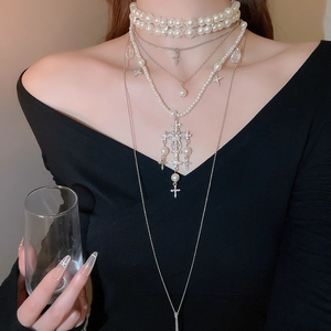 Detail of layered silver cross pendants with shimmering pearls and crystal accents