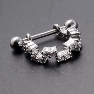 Macro shot of silver stainless steel barbell piercing with sparkling zircon crown inlay