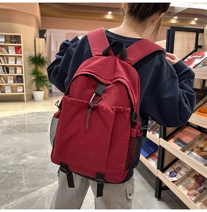 Roter Rucksack mit mehreren Taschen auf dem Rücken in einer Bibliothek-Umgebung