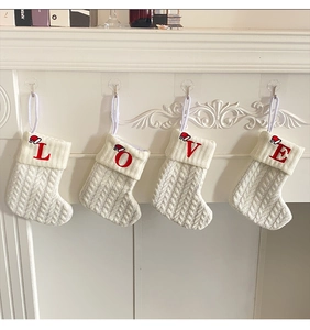 Close-up of four white knit Christmas stockings with red embroidered LOVE letters on a mantel