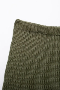 Dettaglio macro della trama in maglia spessa verde militare e polsino a coste