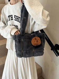 Gray plush checkered underarm bag with a brown bear pendant, worn by a model