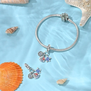 Macro detail of nautical airplane suitcase charms on a silver snake chain bracelet