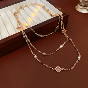 Detail of vintage gold layered necklace with clover enamel pendants on a velvet box