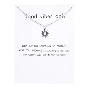 Detail of vintage silver sun pendant on O-chain necklace with positive quote card