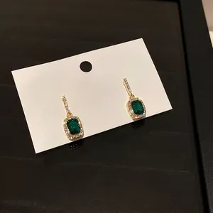 Elegant emerald cut green gemstone stud earrings with sparkling diamonds in gold setting