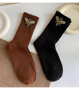 Detailed embroidery of a gold bee on ribbed knit mid-calf socks in black and brown