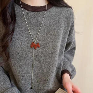 Tiger eye scotty dog pendant necklace with gold chain on grey sweater for elegant look