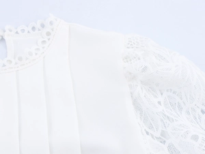 Detail of white women blouse showing lace cutout sleeves and pleated bodice texture