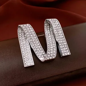 Broche luxueuse en strass lettre M avec base en métal argenté sur cuir de qualité