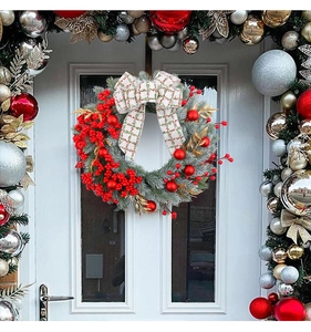 Close-up of Christmas wreath with red berries, pine needles and checkered bow on white door