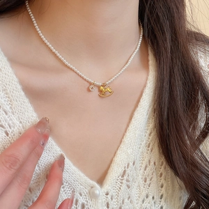 Detail of pearl necklace with a golden rocking horse pendant on a model's neck