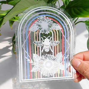 Rainbow prism window sticker featuring bee and flowers in natural sunlight with green plants