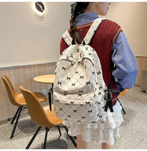 Detail of cream corduroy backpack with black bow pattern and ribbon side decor