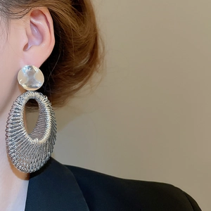 Gros plan de boucles d'oreilles pendantes ovales tissées argentées sur un mannequin