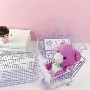 Close-up of light purple metal wire storage basket and mini shopping cart on pink desk