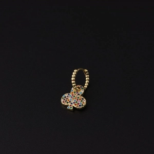 Macro view of golden huggie earring featuring a floral charm set with colorful zircons