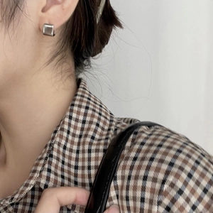 Close-up of a minimalist square silver earring worn on the earlobe with a clean look