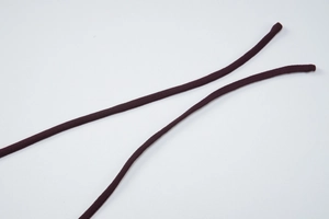 Gros plan de cordons tressés marron foncé avec texture textile détaillée sur fond blanc