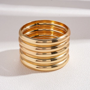 Close-up of five-piece minimalist gold geometric bangle set with polished metallic finish