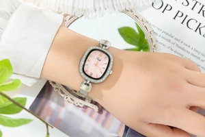 Fashionable women's watch with an oval pink sunburst dial and crystal-encrusted bezel