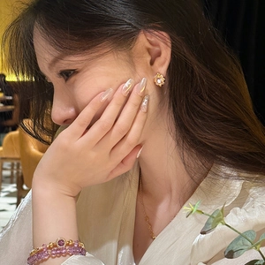 Close-up of elegant 18K gold plated flower earrings with zircon gems on a model