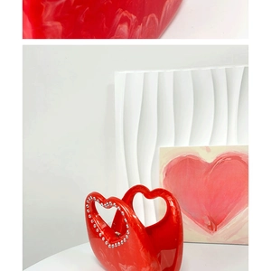 Macro detail of red heart handbag showing marble texture and rhinestone-encrusted handle