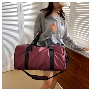 Close-up of burgundy fitness travel bag with black handles and adjustable shoulder strap